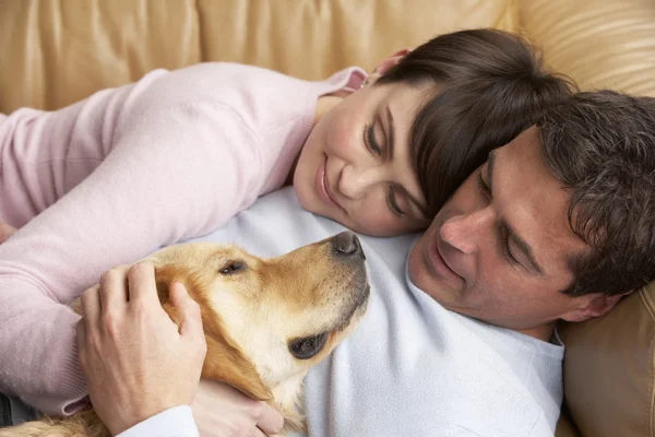 Retrato de pareja relajante en sofá con perro de mascota en casa —  Fotos de Stock