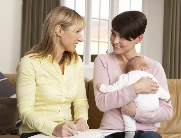 母亲与新生婴儿和健康位访客在家里说话 — 图库照片