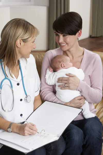 Mãe com bebê recém-nascido conversando com visitante de saúde em casa — Fotografia de Stock