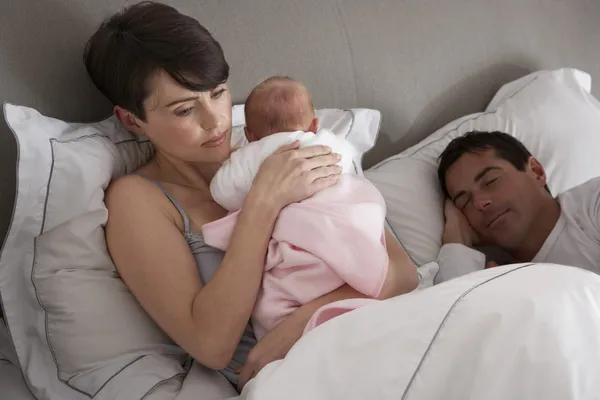Mamma pussar nyfött barn i sängen hemma — Stockfoto