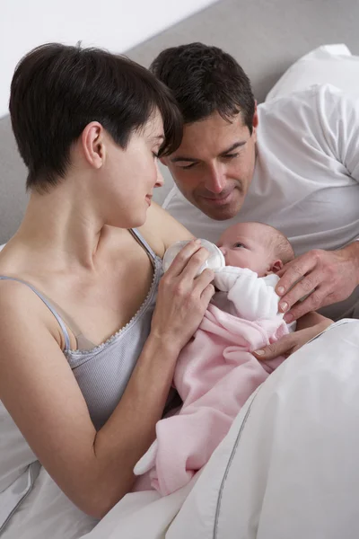 Родители кормят новорожденного ребенка в постели дома — стоковое фото