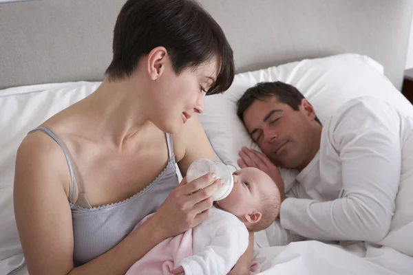Mãe alimentando bebê recém-nascido na cama em casa — Fotografia de Stock