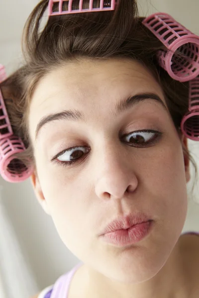 Adolescente com cabelo em rolos puxando um rosto — Fotografia de Stock