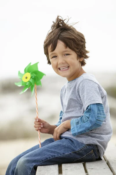 Мальчик держит ветряную мельницу на ветру — стоковое фото
