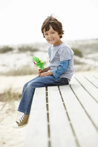 Мальчик на пляже с ветряной мельницей — стоковое фото