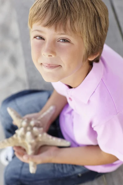 Jovem rapaz ao ar livre segurando estrela do mar — Fotografia de Stock