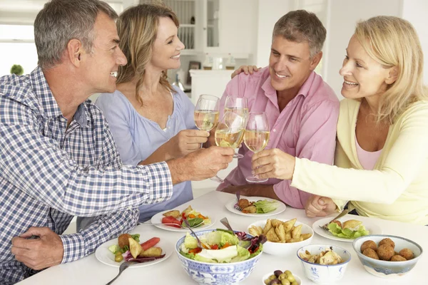 Parejas de mediana edad disfrutando de la comida en casa — Foto de Stock