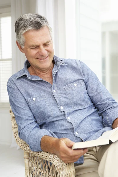 Uomo anziano rilassante a casa con un libro — Foto Stock