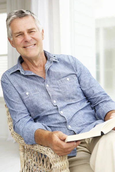 Senior man relaxing at home with a book — Stock Photo, Image