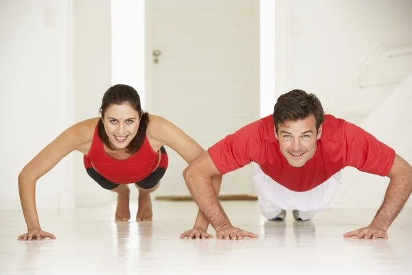 Couple doing push-ups in home gym — Stock Photo, Image