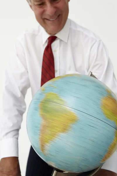 Hombre de negocios senior girando globo — Foto de Stock
