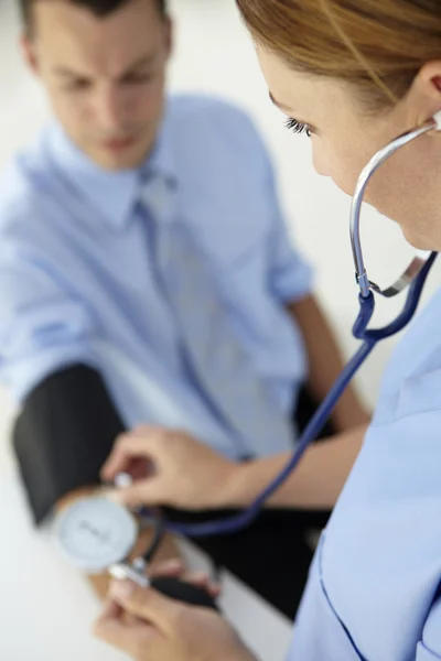 Doctor taking young man's blood pressure — Stock Photo, Image
