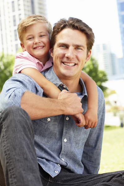 Человек, сидящий в городском парке с маленьким сыном — стоковое фото