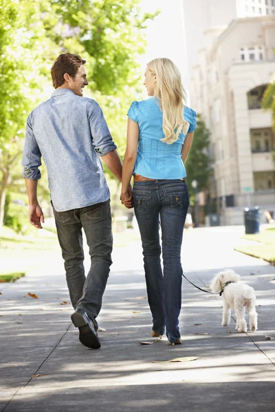 Paar geht mit Hund in Stadtstraße spazieren — Stockfoto