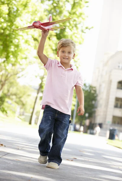 Junge mit Spielzeugflugzeug auf Straße — Stockfoto