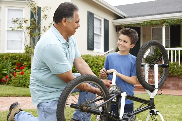 Хлопчик і дідусь фіксують велосипед — стокове фото