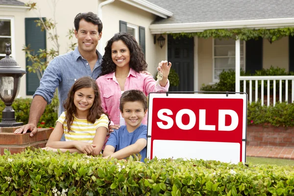 Hispanic family outside home with sold sign — Stock Photo, Image