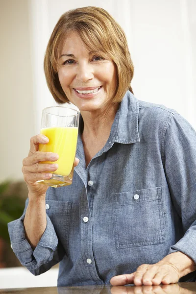 Mulher de meia idade bebendo suco de laranja — Fotografia de Stock