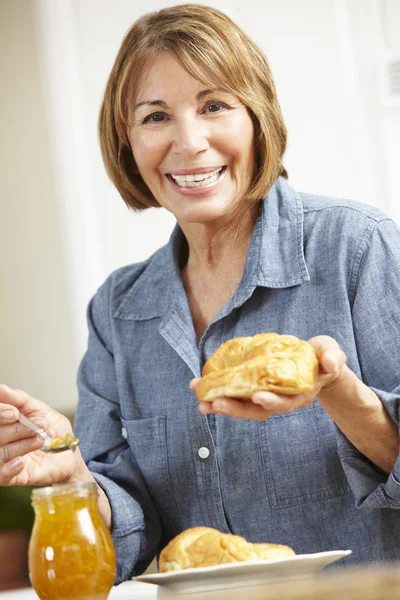 クロワッサンを食べ年齢女性半ば — ストック写真