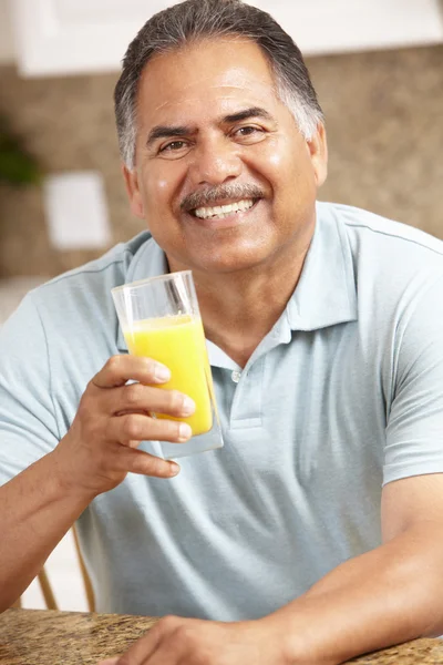 Старший мужчина пьет апельсиновый сок — стоковое фото
