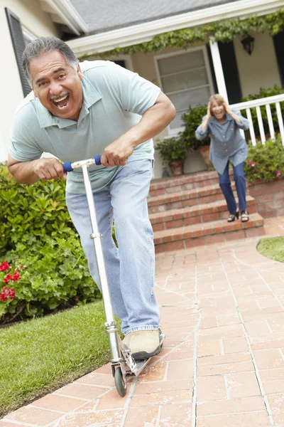 Senior couple playing with children's scooter — Stock Photo, Image