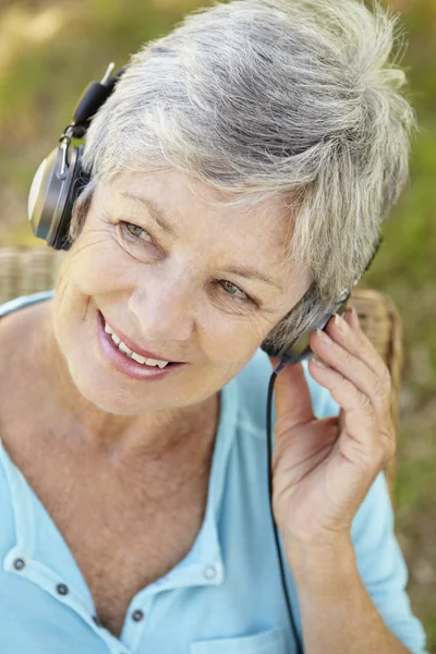 Starší žena s sluchátka — Stock fotografie
