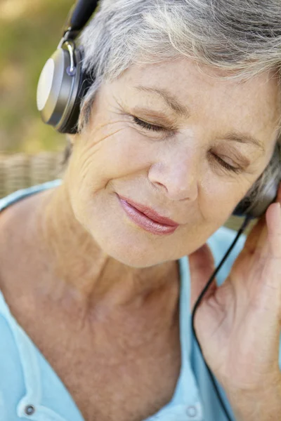 Äldre kvinna med hörlurar — Stockfoto