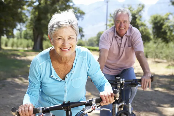Starszy para w kraju na rowerze — Zdjęcie stockowe