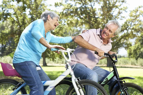 Couple aîné jouant sur des vélos pour enfants — Photo