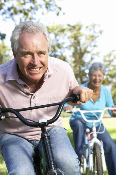 Seniorenpaar spielt auf Kinderfahrrädern — Stockfoto
