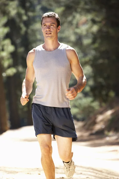 Young man running along country lane — Stock Photo, Image