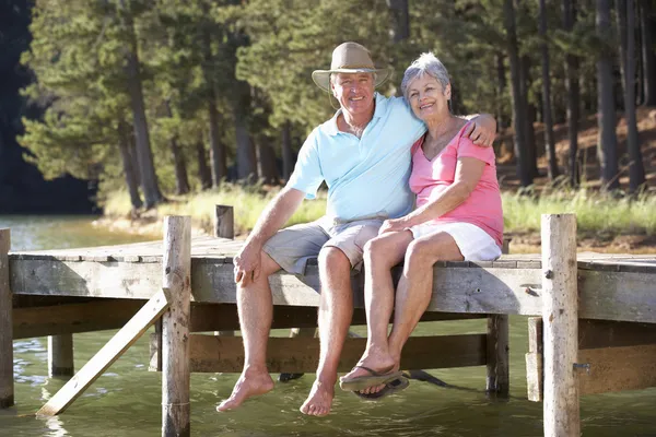 Старша пара сидить біля озера — стокове фото