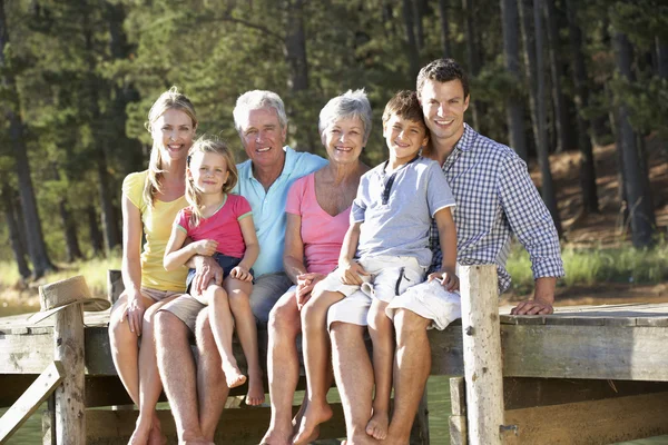 3 generation familj sitter vid sjön — Stockfoto