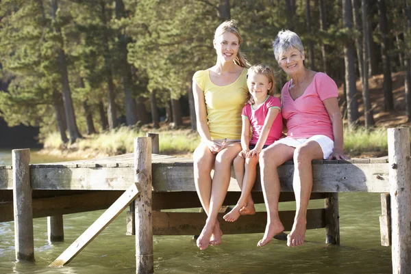 Mother,daughter and grandmother sitting by lake — Stock Photo, Image