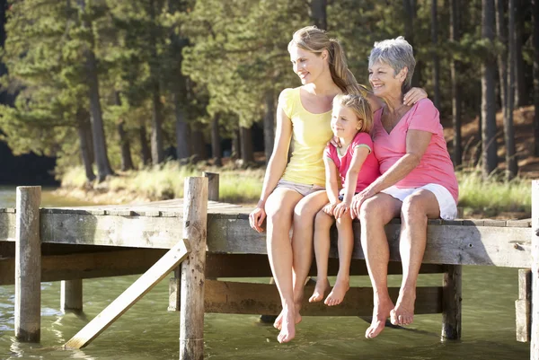 Mère, fille et grand-mère assis au bord du lac — Photo