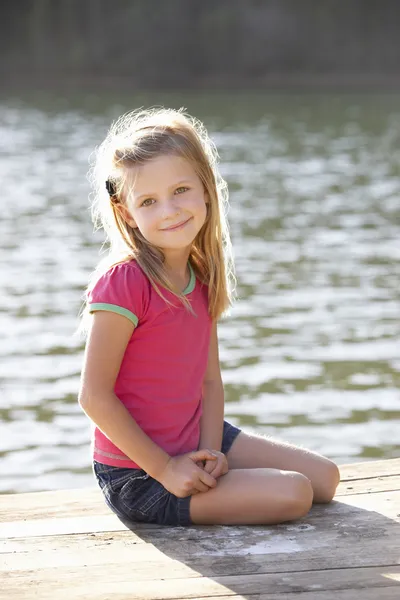 Ung flicka sitter vid sjön — Stockfoto
