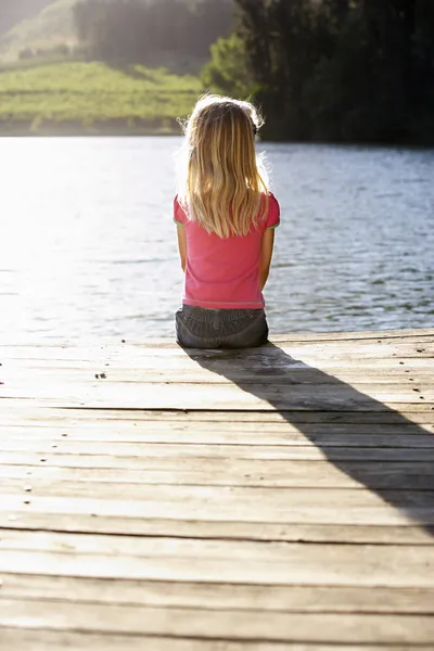 Giovane ragazza seduta vicino al lago — Foto Stock