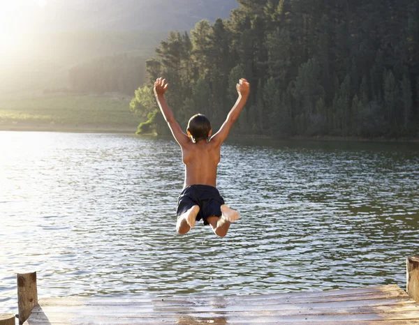 Jeune garçon sautant dans le lac — Photo