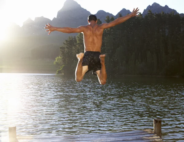 stock image Young man jumping into lake