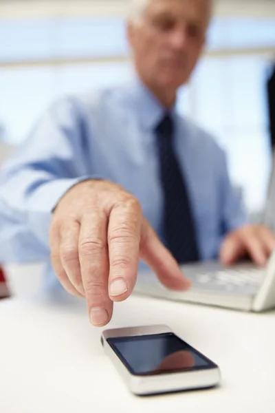 Senior affärsman med laptop och telefon — Stockfoto