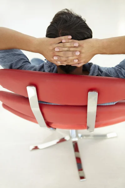 Ung man avkopplande i röd stol — Stockfoto