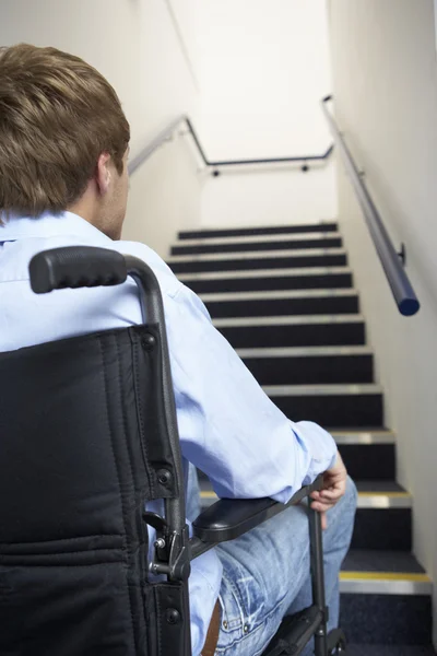 Człowiek na wózku inwalidzkim u podnóża schodów — Zdjęcie stockowe