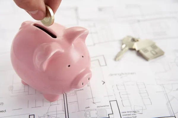 Piggybank com planos de casa e chaves — Fotografia de Stock