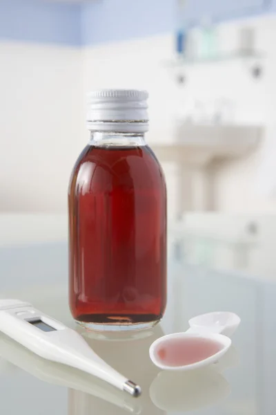 Термометр и лекарства на полке в ванной комнате — стоковое фото