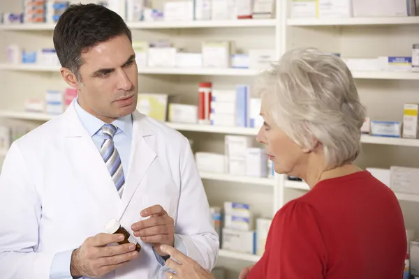 Американский фармацевт с пожилой женщиной в аптеке — стоковое фото