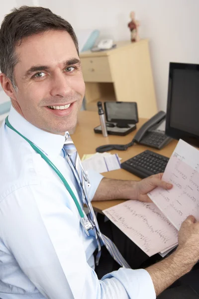 Британский врач общей практики сидит за столом — стоковое фото
