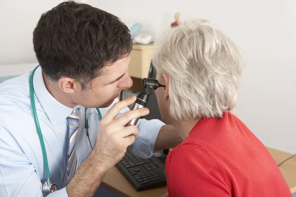 Brittiska läkare granskar äldre kvinnas öra — Stockfoto