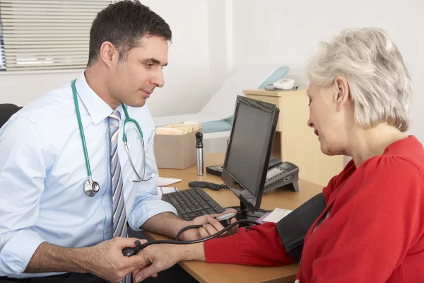 Brytyjski lekarz przy starszych kobiety ciśnienie krwi — Zdjęcie stockowe