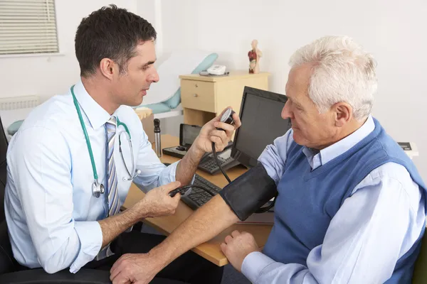 Britský lékař, přičemž starší muž krevní tlak — Stock fotografie