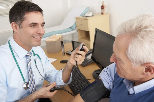 Brytyjski lekarz biorąc starszy człowiek ciśnienie krwi — Zdjęcie stockowe
